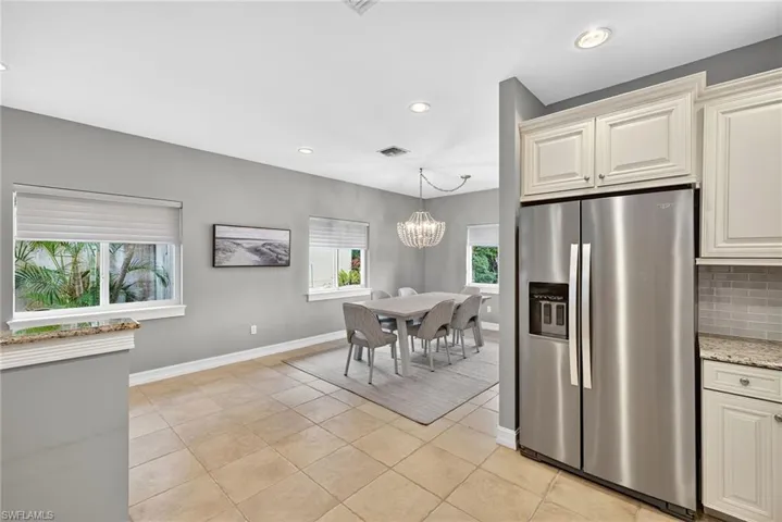 Kitchen featuring stainless steel fridge with ice dispenser, recessed lighting, light stone countertops, tasteful backsplash, and light tile patterned floors