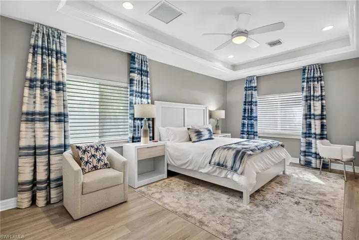 Bedroom with a tray ceiling, wood finished floors, recessed lighting, and ceiling fan