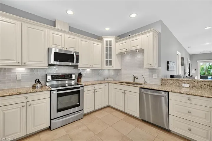 Kitchen with stainless steel appliances, light stone countertops, light tile patterned floors, decorative backsplash, and recessed lighting