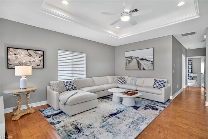 Living area featuring a tray ceiling, light wood finished floors, recessed lighting, and ceiling fan