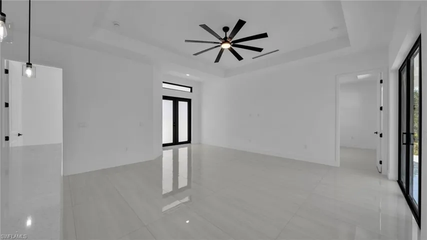 Spare room featuring a raised ceiling, french doors, light tile patterned floors, and ceiling fan