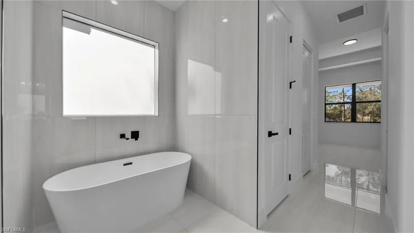 Bathroom featuring a soaking tub, recessed lighting, and tile patterned flooring