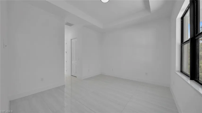 Empty room featuring a tray ceiling and baseboards