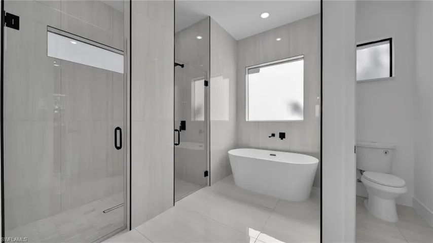 Bathroom featuring a freestanding tub, a shower stall, and light tile patterned floors