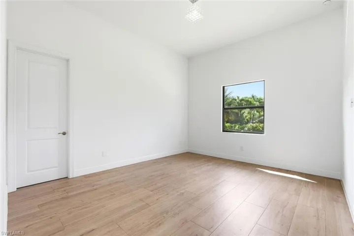 Wood-finish flooring, white walls, white trim, square window, and a white paneled door
