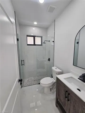 Bathroom with vanity, a stall shower, light tile patterned floors, and recessed lighting