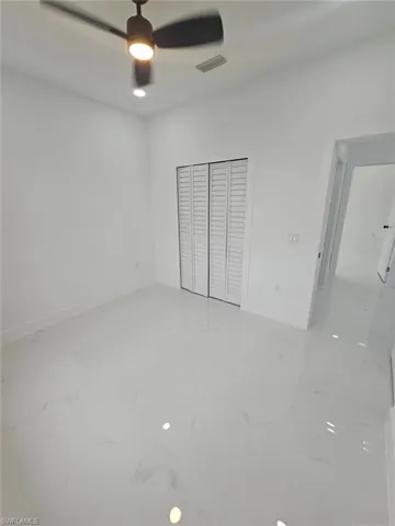 Unfurnished bedroom with light marble finish flooring, a closet, and a ceiling fan