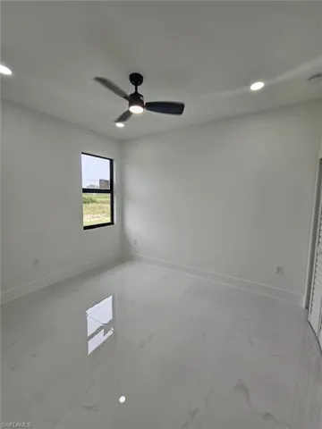 Unfurnished room with a ceiling fan, recessed lighting, and light marble finish flooring