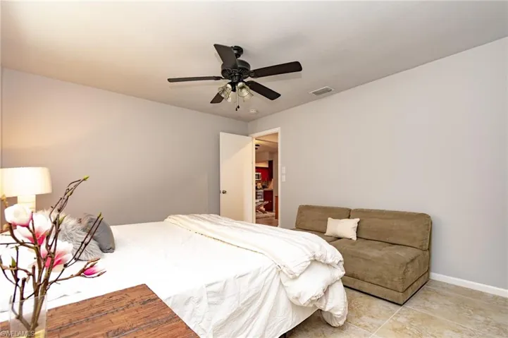 Interior space featuring light gray walls, a dark bronze ceiling fan with integrated lighting, and neutral-toned tile flooring