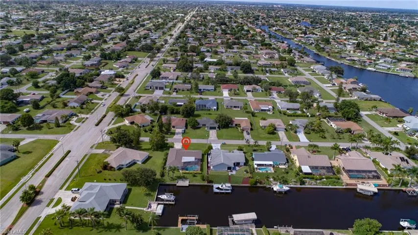 Canal-front property featuring a private boat dock, pool enclosure, and a concrete paver driveway