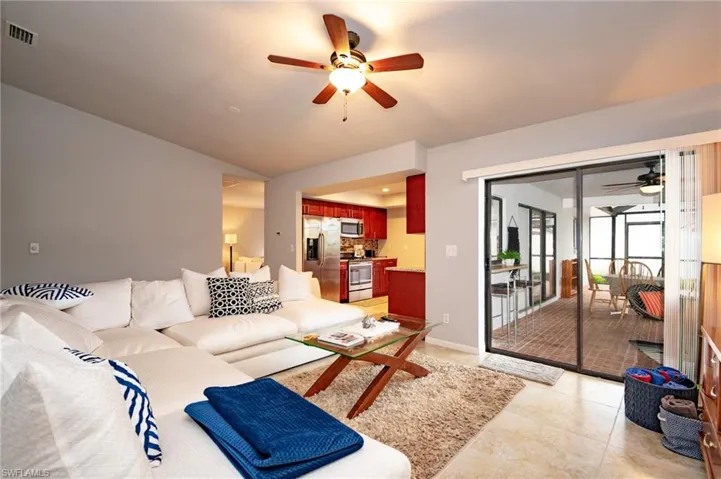 Spacious living area featuring neutral wall tones, a vaulted ceiling, and a ceiling fan
