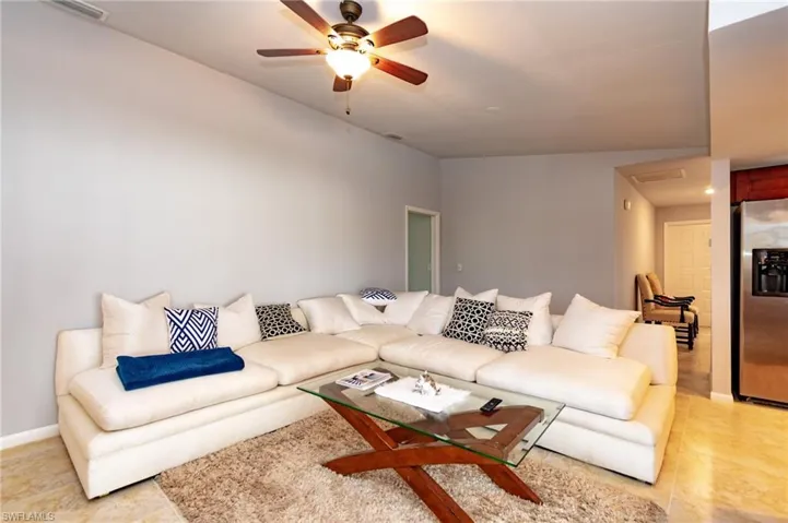 Living area featuring light gray walls, a ceiling fan with integrated lighting, and tile flooring