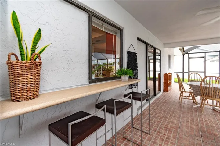 Covered outdoor patio featuring brick-finish flooring, a built-in serving bar, and multiple sliding glass doors