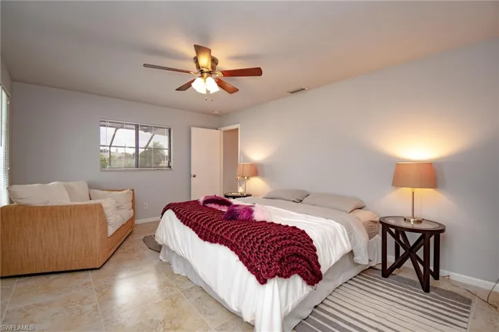 Bedroom featuring tile flooring, a ceiling fan with integrated lighting, window with horizontal blinds, and light gray wall paint