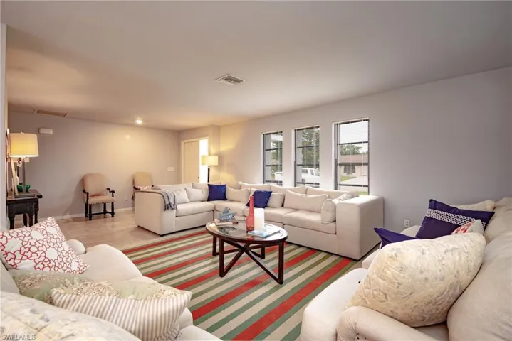 Spacious living area featuring light-toned walls, recessed lighting, and multiple windows