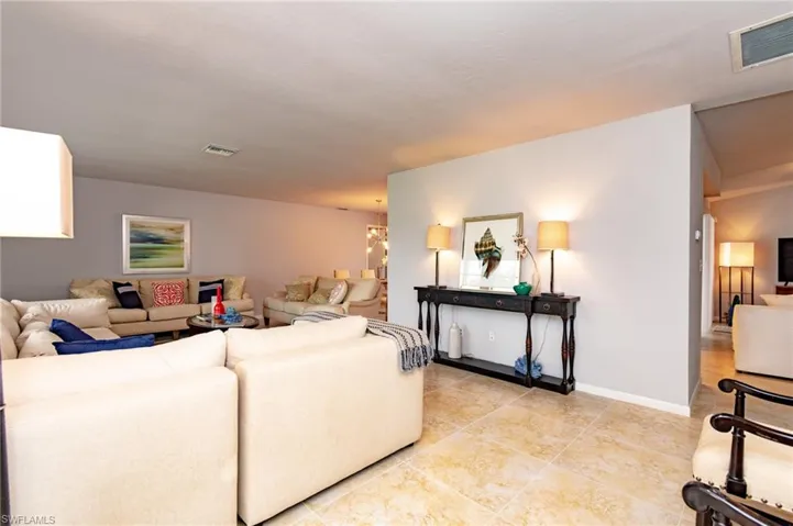 Spacious living area featuring light-toned tile flooring throughout, smooth ceilings, and neutral wall paint