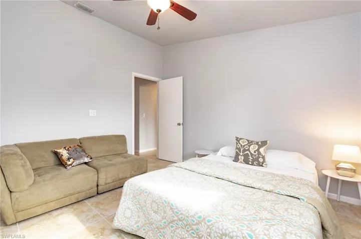 Interior room featuring light gray walls, tile flooring, a ceiling fan with light fixture, and an open doorway