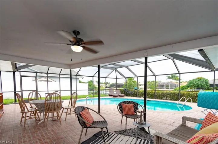Screened lanai featuring a swimming pool, brick paver flooring, and a ceiling fan with integrated lighting