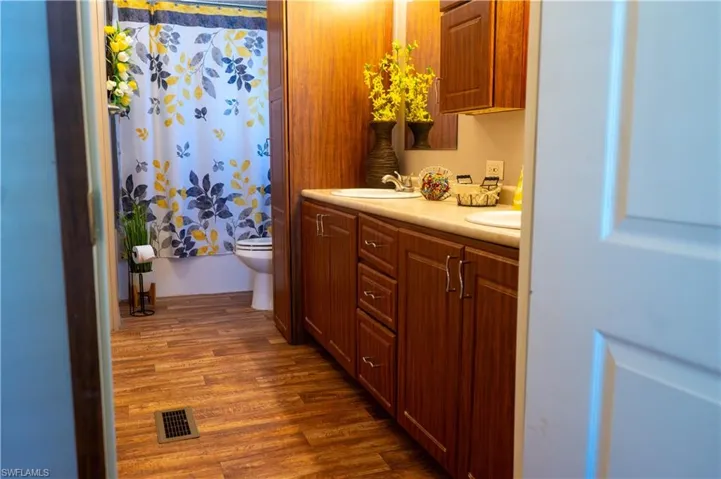 Bathroom with hardwood / wood-style floors, curtained shower, vanity, and toilet