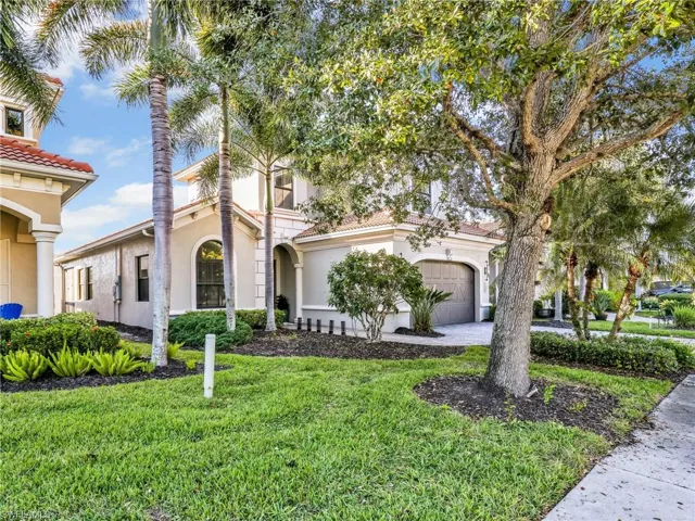 Mediterranean / spanish-style home with stucco siding, a front lawn, a tiled roof, and driveway