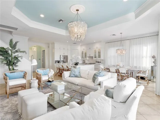 Living area with a raised ceiling, a chandelier, ornamental molding, light tile patterned floors, and recessed lighting