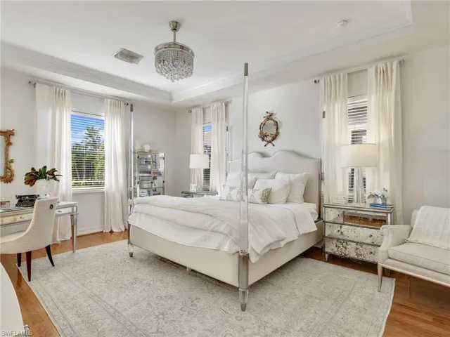 Bedroom featuring a raised ceiling, wood finished floors, and crown molding