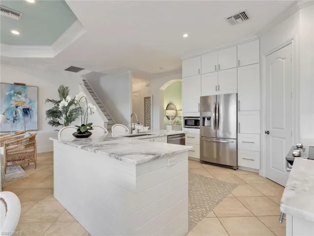 Kitchen featuring ornamental molding, stainless steel appliances, arched walkways, recessed lighting, and white cabinetry