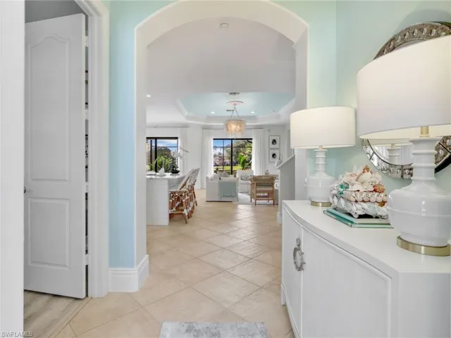 Corridor featuring a tray ceiling and light tile patterned floors