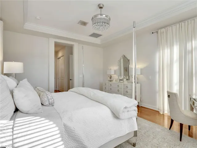 Bedroom with light wood-type flooring, ornamental molding, and a tray ceiling