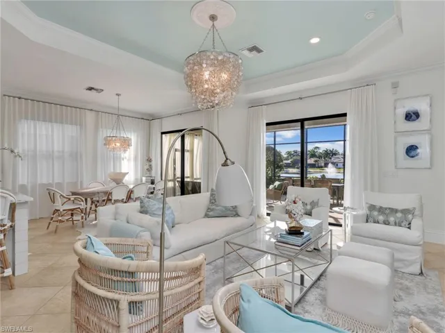 Living area with light tile patterned floors, a chandelier, a tray ceiling, crown molding, and recessed lighting