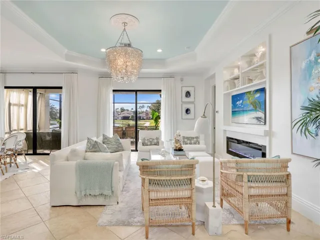 Living area featuring a chandelier, a tray ceiling, crown molding, light tile patterned flooring, and recessed lighting