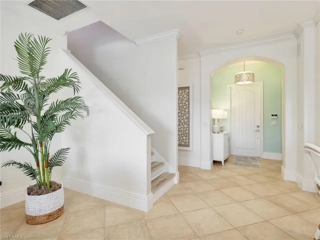 Entryway featuring arched walkways, ornamental molding, stairway, and light tile patterned floors
