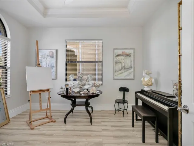 Sitting room with a raised ceiling, light wood-type flooring, and crown molding