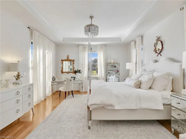 Bedroom featuring a tray ceiling, light wood-style floors, and ornamental molding
