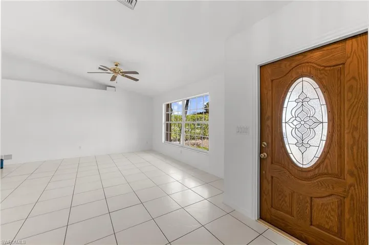 Foyer entrance with a ceiling fan, lofted ceiling, and light tile patterned flooring