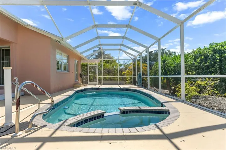Relaxing pool / spa featuring a sunroom, glass enclosure, and a patio