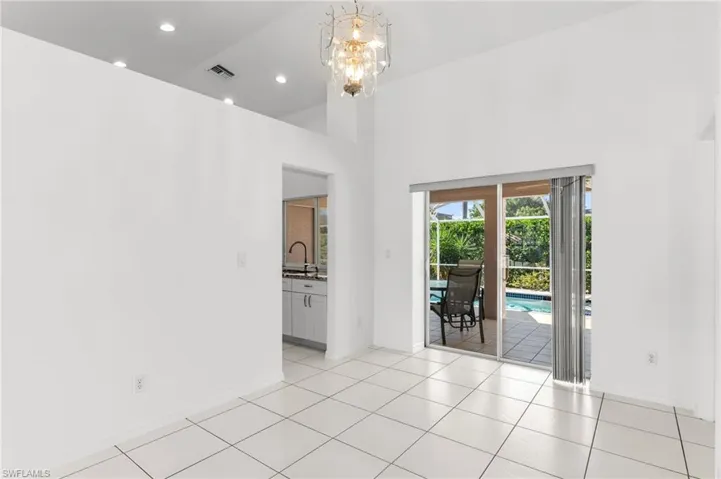 Unfurnished room with suspended lighting, light tile patterned floors, and a high ceiling