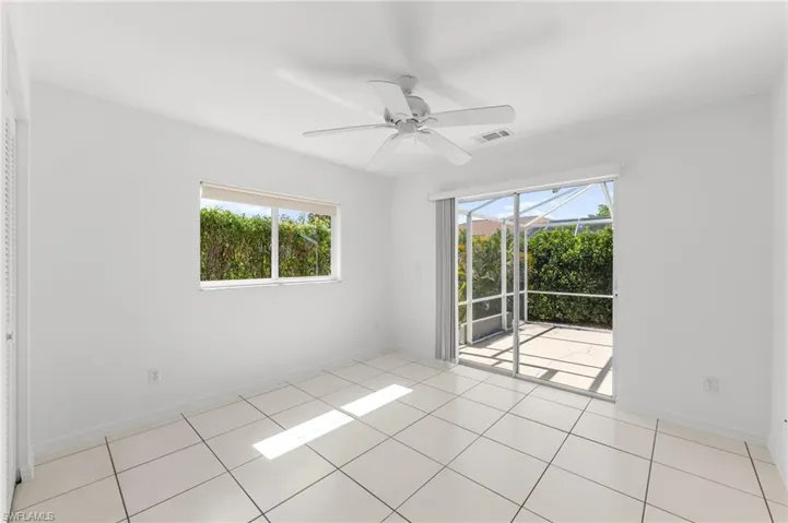Empty room with a sunroom, ceiling fan, plenty of natural light, and light tile patterned floors