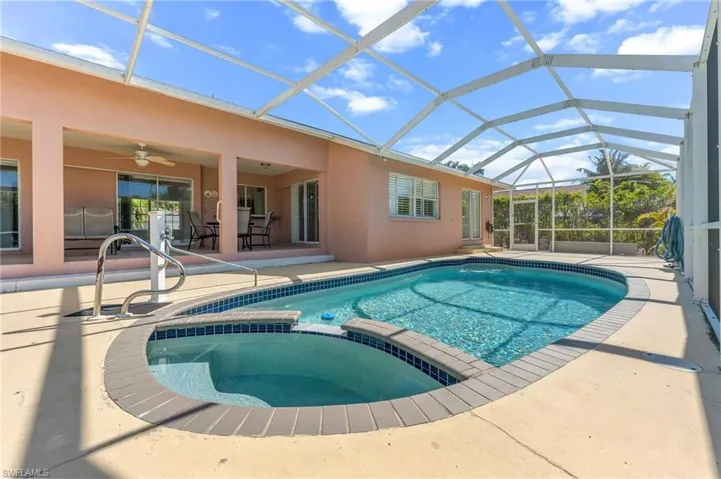 Integrated pool / hot tub with a sunroom, a patio area, glass enclosure, and outdoor dining area