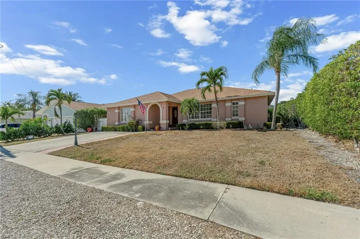 Ranch-style home with stucco siding, driveway, and a front lawn