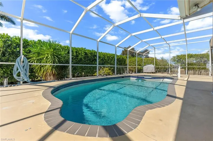 Swimming pool with glass enclosure, a sunroom, a patio, and an in-ground hot tub
