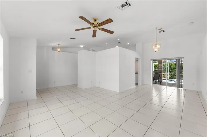 Spare room featuring a ceiling fan, light tile patterned floors, suspended lighting, and vaulted ceiling