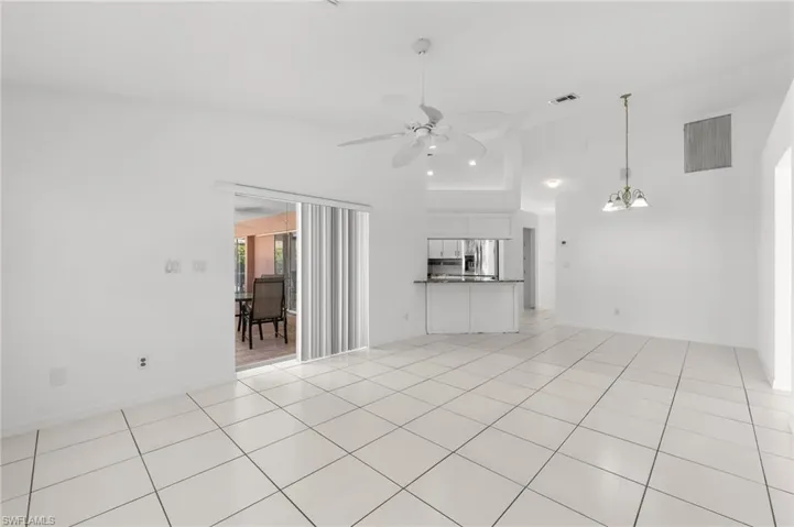 Unfurnished living room with a ceiling fan, a high ceiling, and light tile patterned floors