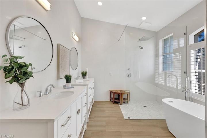 Beautifully updated primary bathroom with tile floors double vanity sinks and doorless glass shower