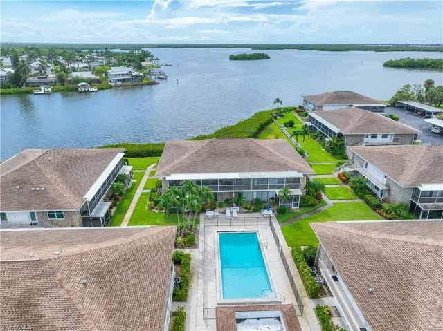 Aerial perspective of suburban area featuring a nearby body of water and a pool