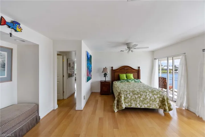 Bedroom with access to outside, a water view, light wood-type flooring, and ceiling fan