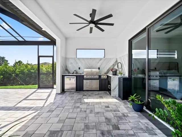 Unfurnished sunroom with an outdoor kitchen, a ceiling fan, and a patio area