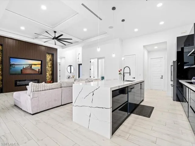Kitchen featuring pendant lighting, a ceiling fan, an island with sink, modern cabinets, and coffered ceiling