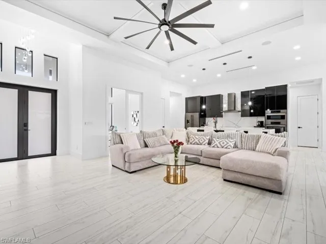 Living area with a ceiling fan, french doors, a high ceiling, recessed lighting, and light wood finished floors