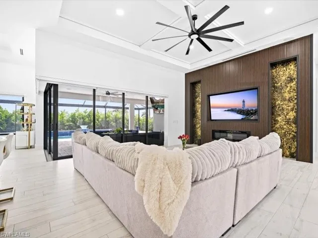 Living area featuring a sunroom, an accent wall, a ceiling fan, and recessed lighting